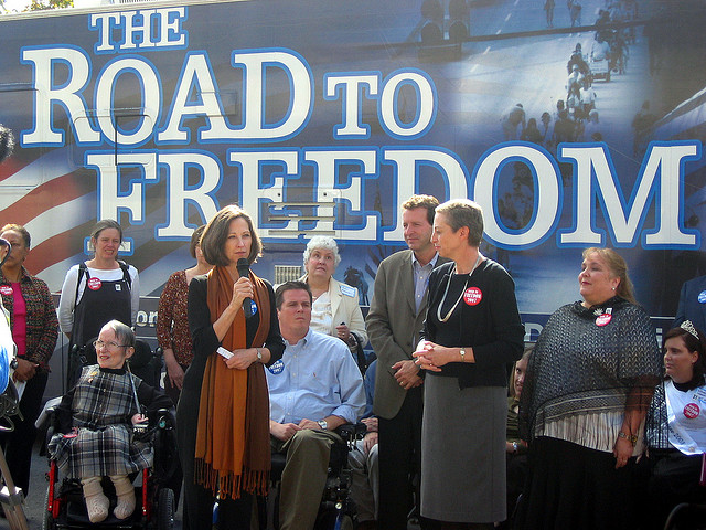 Susan Edwards, Frist Center Executive Director and CEO, speaks to visitors, joined by Carol Westlake, Tennessee Disability Coalition Executive Director, and Jim Ward, with the Road to Freedom bus tour