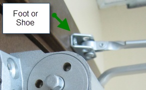 Picture of a door closer that also shows the foot or shoe hardware above the closer.